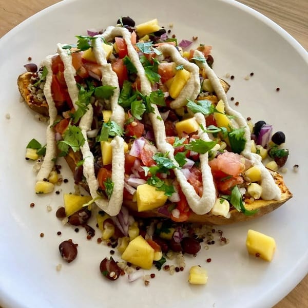 Sweet potato topped with salsa, corn, black beans, quinoa, and a creamy white sauce.
